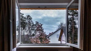 A window with a view of a house and trees. - Motel Zur Dachsbaude (Wandlitz)