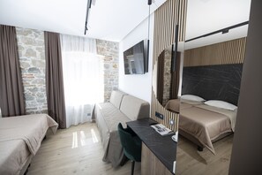 A modern hotel room with a stone accent wall, a sofa, a desk, and a bed. - A Heritage Hotel Split (Split)