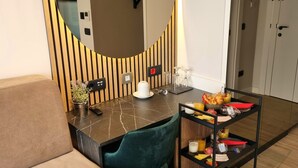A modern room with a marble table, a green chair, a small plant, and a breakfast tray with croissants and juice. - A Heritage Hotel Split (Split)