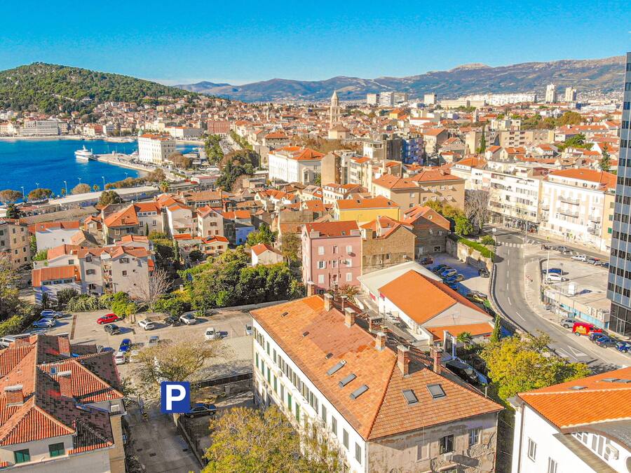 Un paisaje urbano costero con una mezcla de edificios históricos y modernos, una iglesia destacada y una vista despejada del mar.