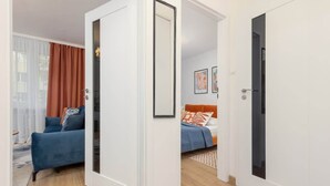 A modern hotel room with a blue sofa, a bed with orange bedding, and a large mirror. - Apartment in the center of Warsaw | Balcony and Workspace (Warszawa)