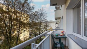 A balcony with a table and chairs, overlooking a tree-lined street. - Apartment in the center of Warsaw | Balcony and Workspace (Warszawa)