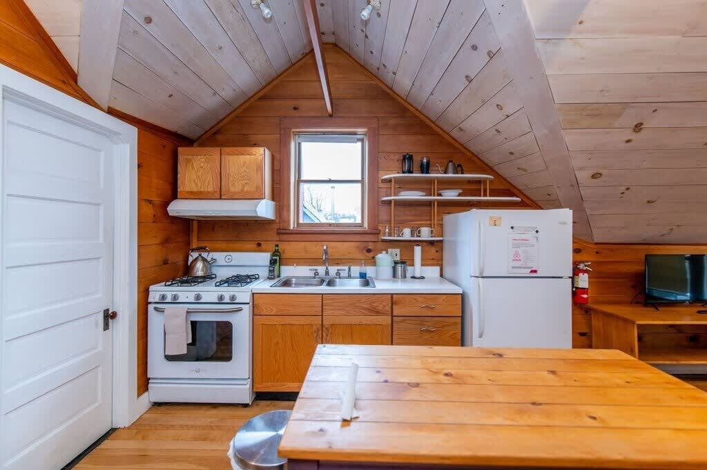 Une cuisine de taille réduite, avec des meubles de rangement en bois, une cuisinière, un évier et un réfrigérateur.