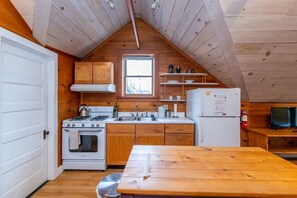 Una cocina pequeña con armarios de madera, un fogón, un lavamanos y un refrigerador.