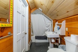 Un baño pequeño y funcional con ducha, inodoro y lavamanos.