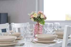 A dining table set with plates, glasses, and a vase with flowers.