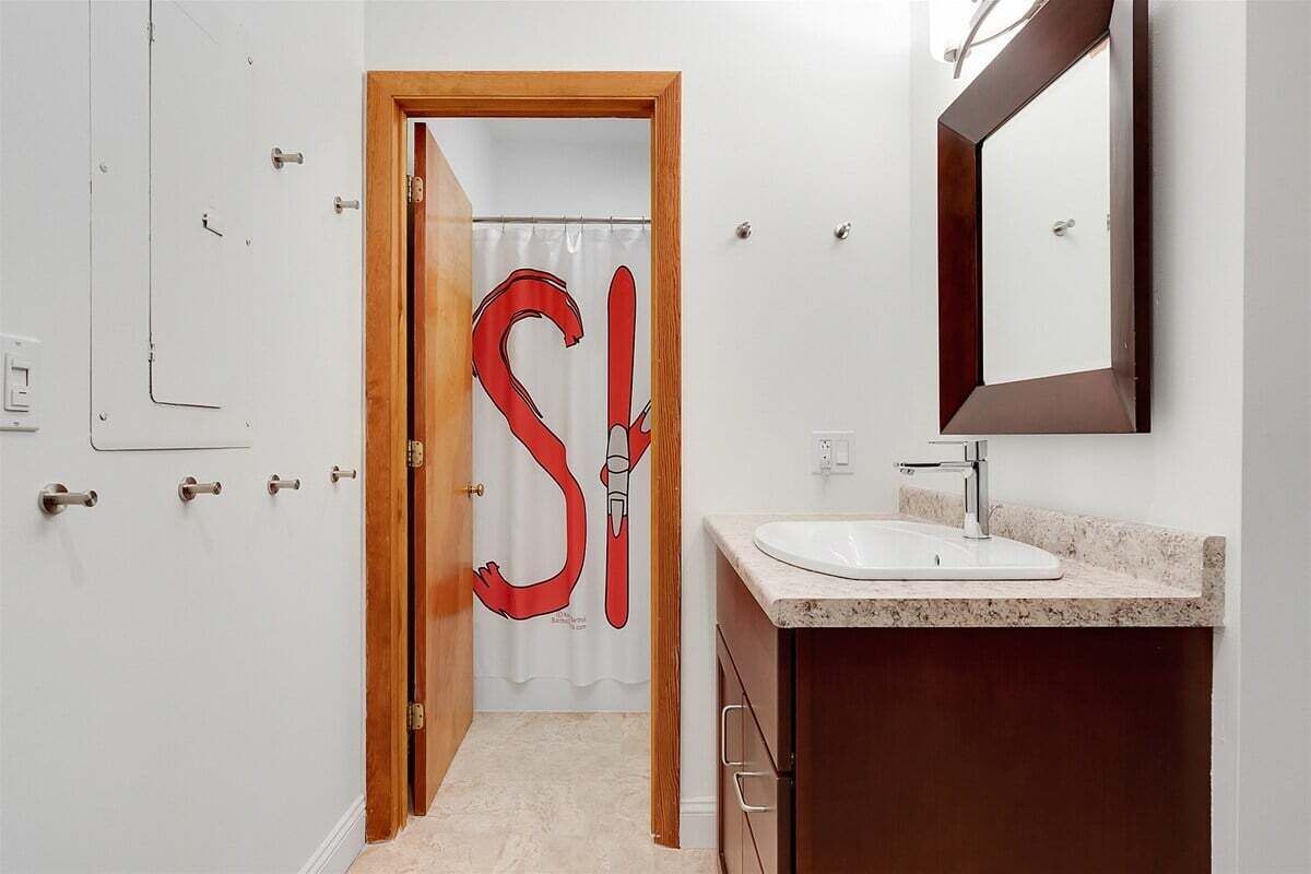 A bathroom with a white sink, a mirror, and a door with a red 'S' sign.