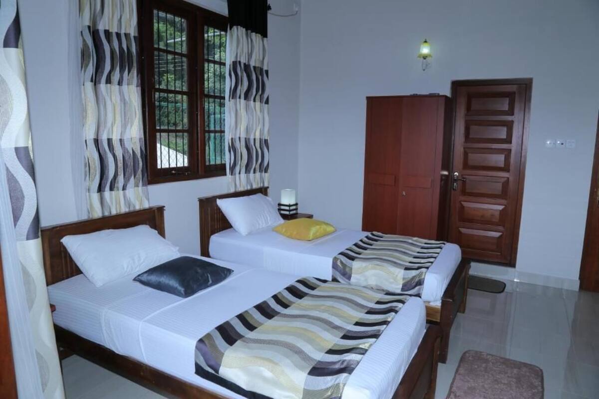 Quarto com duas camas, um guarda-roupa de madeira e uma porta.