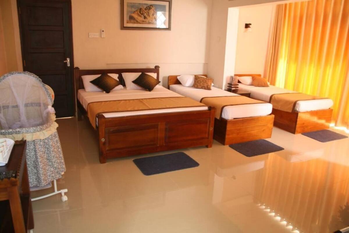 Quarto de hotel com uma cama grande, um sofá-cama, um armário de madeira e uma pequena mesa.