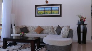 Un salon avec un canapé, une table basse et une œuvre d’art encadrée accrochée au mur.