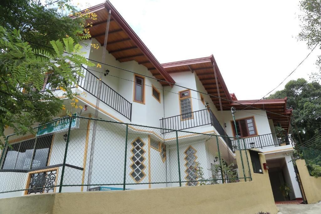 A two-story house with a balcony, a staircase, and a fenced yard.
