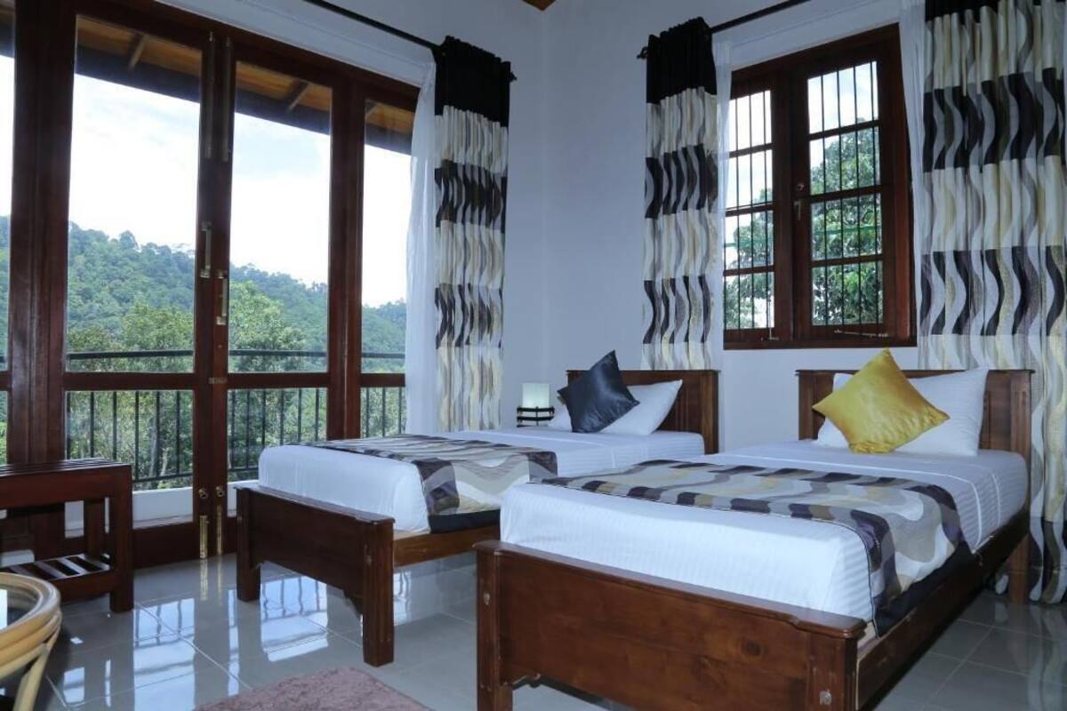 Quarto com duas camas, janelas amplas e vista para o exterior.