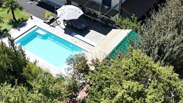 Ein zweigeschossiges Haus mit Schwimmbad, überdachter Terrasse und Garten.