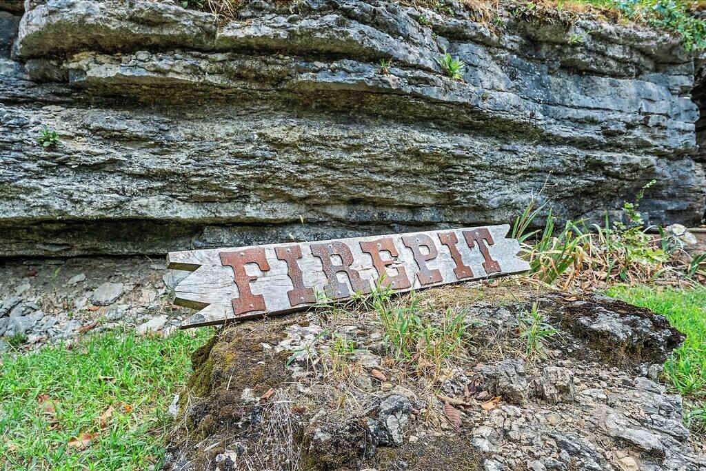 Un panneau en bois portant le mot « FEU », placé sur un rocher, avec de l’herbe qui pousse autour.