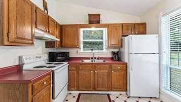 A kitchen with wooden cabinets, a white stove, a microwave, and a refrigerator.