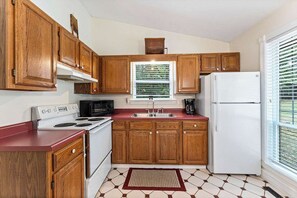 A kitchen with wooden cabinets, a white stove, a microwave, and a refrigerator. - King Bed, View & 2-Person Spa Tub, Private Hiking (Eureka Springs)