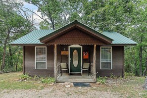 A cabin with a porch, two chairs, and a door with a sign.