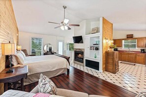 A bedroom with a bed, bedside table, and a ceiling fan. - King Bed, View & 2-Person Spa Tub, Private Hiking (Eureka Springs)
