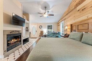 Une chambre avec une cheminée, un lit, un ventilateur de plafond et une vue sur l’extérieur.