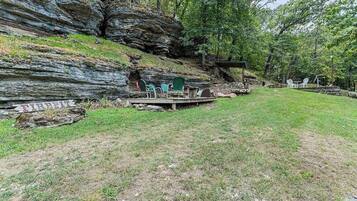 A natural outdoor setting with a seating area, a fire pit, and a wooden structure.