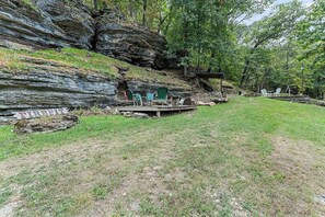 A natural outdoor setting with a seating area, a fire pit, and a wooden structure.