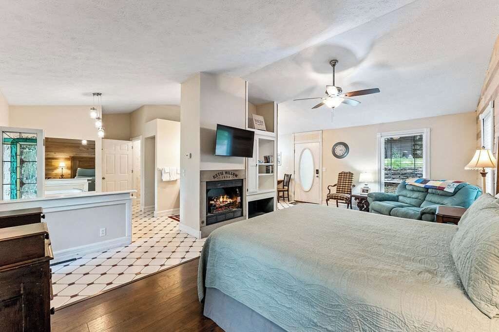 Un dormitorio con cama, televisión, chimenea y ventilador de techo.