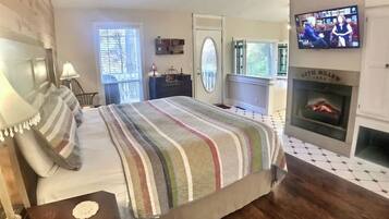 King bed in front of a warm electric fireplace and TV.