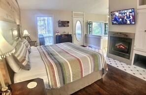 King bed in front of a warm electric fireplace and TV.