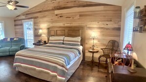 Une chambre avec un grand lit, un plafond en bois et une petite table avec une lampe.