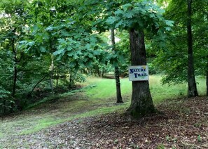 Un panneau indiquant le début d’un sentier de randonnée dans une zone boisée.
