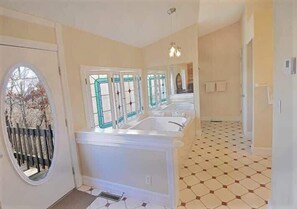 Ein geräumiges Badezimmer mit einer großzügigen Badewanne, einer Dusche und einem WC. Ein Fenster bietet Blick auf Bäume.