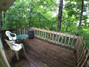 Eine Holzterrasse mit Tisch und Stühlen, umgeben von einem Holzzaun und üppiger Bepflanzung.
