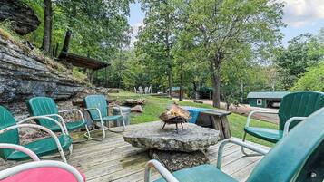 A wooden deck with outdoor seating, a fire pit, and a view of a natural landscape.