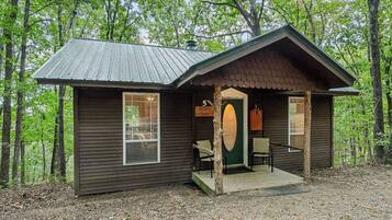 A cabin with a porch, a door, and a window.