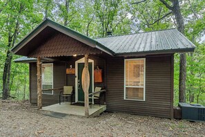 Une petite cabane avec un porche, une porte portant l’inscription « 5 », et un banc à l’extérieur.