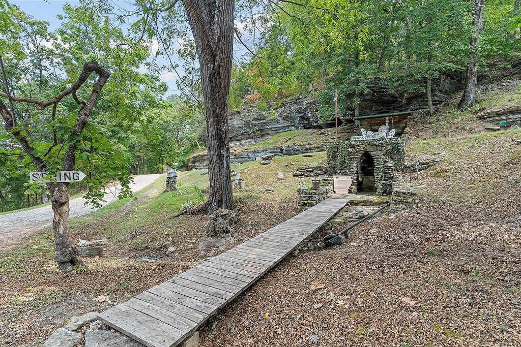 A wooden boardwalk leading to a stone structure in a wooded area.