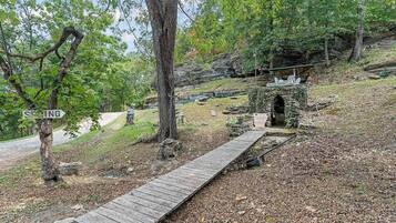 A wooden boardwalk leading to a stone structure in a wooded area.