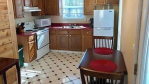A compact kitchen with wooden cabinets, a microwave, a stove, a sink, and a refrigerator.