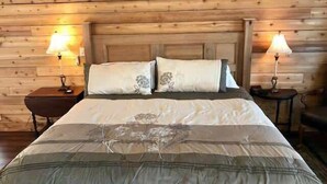 A wooden-paneled room with a bed, two bedside tables, and two lamps.