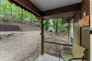 A covered porch with a bench, a wooden fence, and a sign indicating the number 5. - Romantic Ozark Cabin | Spa Tub • Trails • Cave (Eureka Springs)