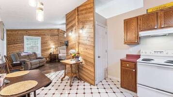 Un espacio habitable compacto con comedor, sofá, cocina con armarios de madera y estufa blanca.