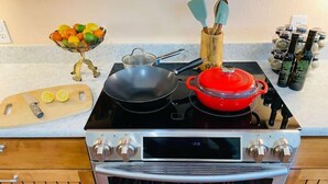 A kitchen with a stove, a red pot, a frying pan, a bowl of fruit, and a cutting board. - Near Marina, Kitchen, FAST WiFi, Hiking near by! (Holiday Island)