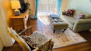 A cozy living room with a sofa, ottoman, and a wooden chair. A lamp and a birdcage are on a side table. - Near Marina, Kitchen, FAST WiFi, Hiking near by! (Holiday Island)