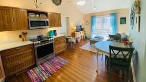 A compact kitchen with wooden cabinets, a microwave, and a stove. There is a dining area with a table and chairs, and a ceiling fan. - Near Marina, Kitchen, FAST WiFi, Hiking near by! (Holiday Island)