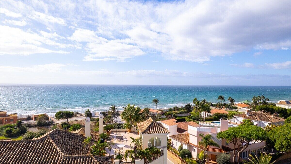 Zona residencial costera con edificios, una playa y cielo despejado.