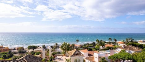 A coastal residential area with buildings, a beach, and a clear sky.
