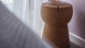 Una mesa de piedra con la palabra 'CHAMPAGNE' grabada, ubicada cerca de una ventana con cortinas traslúcidas.