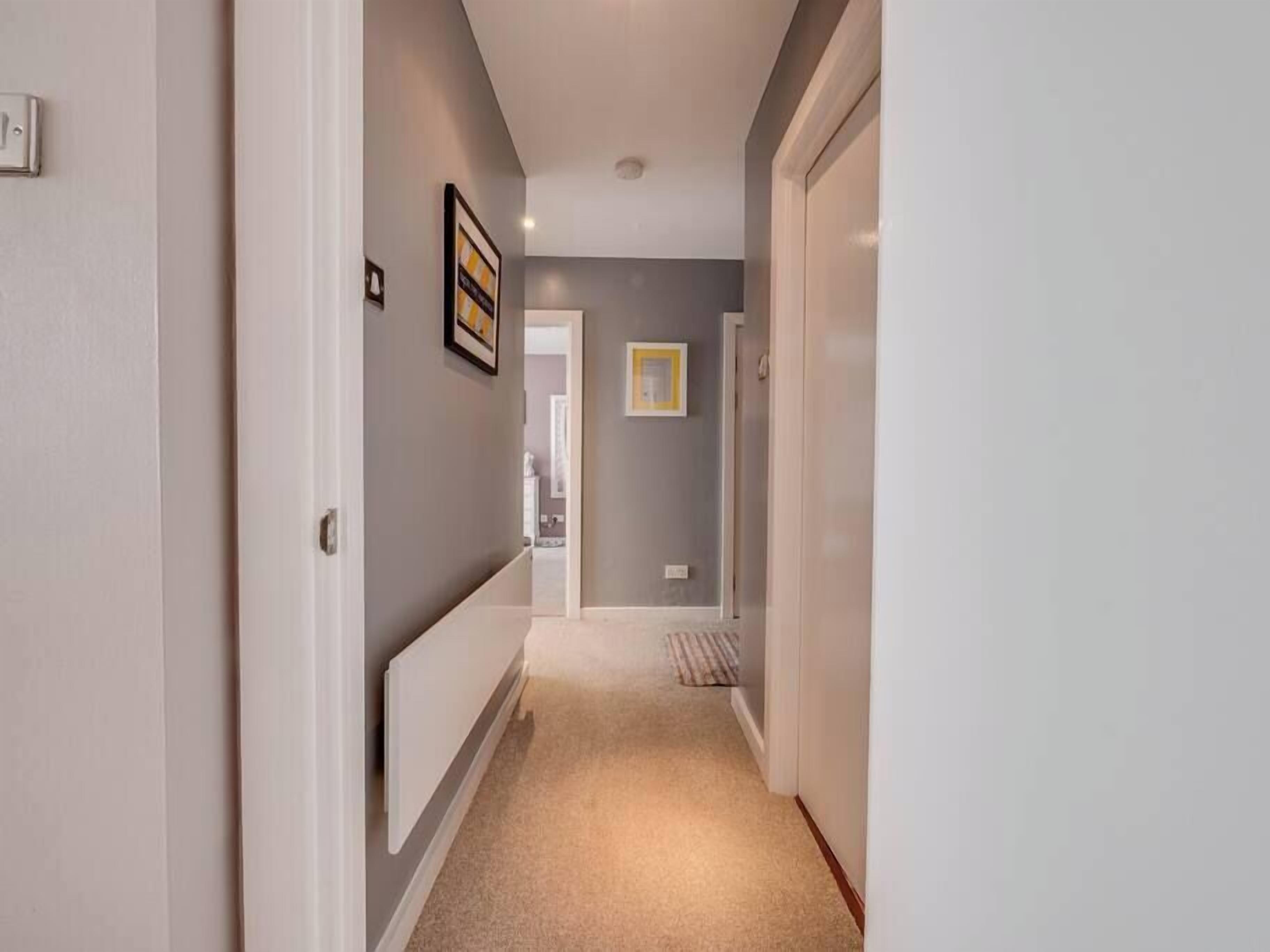 A hallway with a radiator, a door, and a framed picture on the wall.