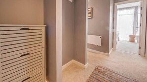 Un pasillo con un radiador, un perchero y una puerta que da a un baño.