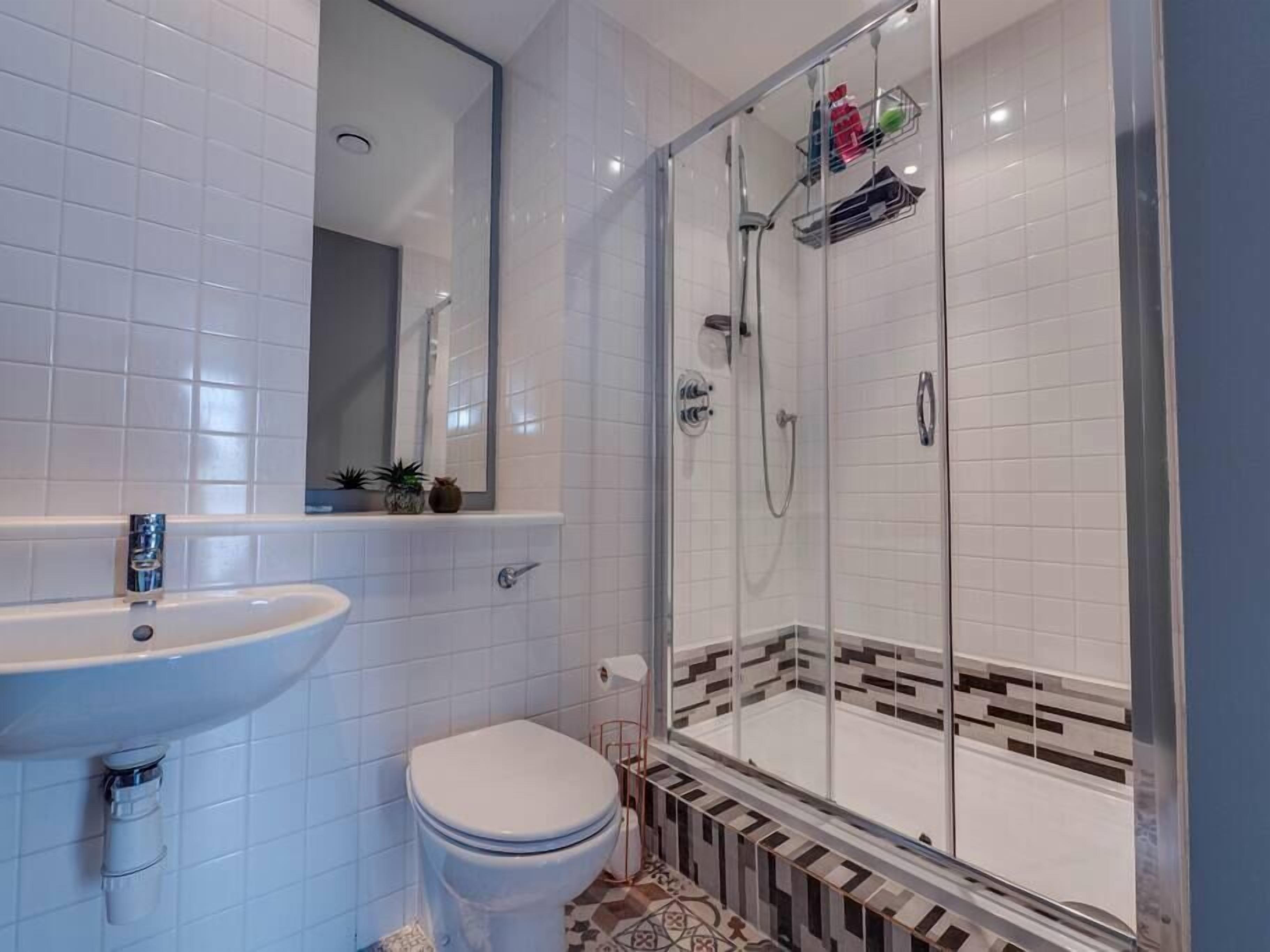 A bathroom with a glass-enclosed shower, a sink, and a toilet.